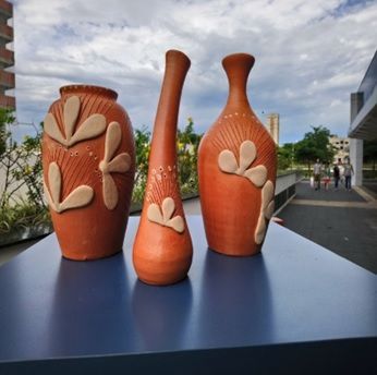 Três vasos de barro estão sobre uma mesa azul