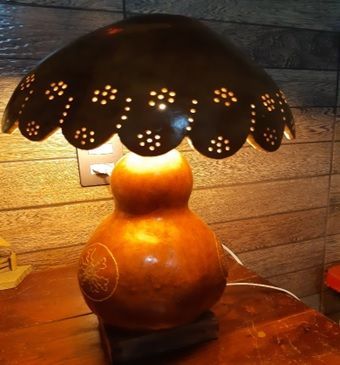 Uma lâmpada feita de cabaça está sobre uma mesa de madeira