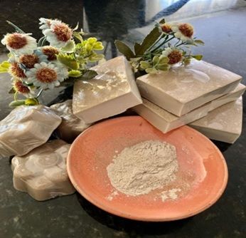 Uma pilha de sabonetes e uma tigela de pó sobre uma mesa.