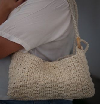 Uma pessoa vestindo uma camisa branca e uma bolsa de crochê branca