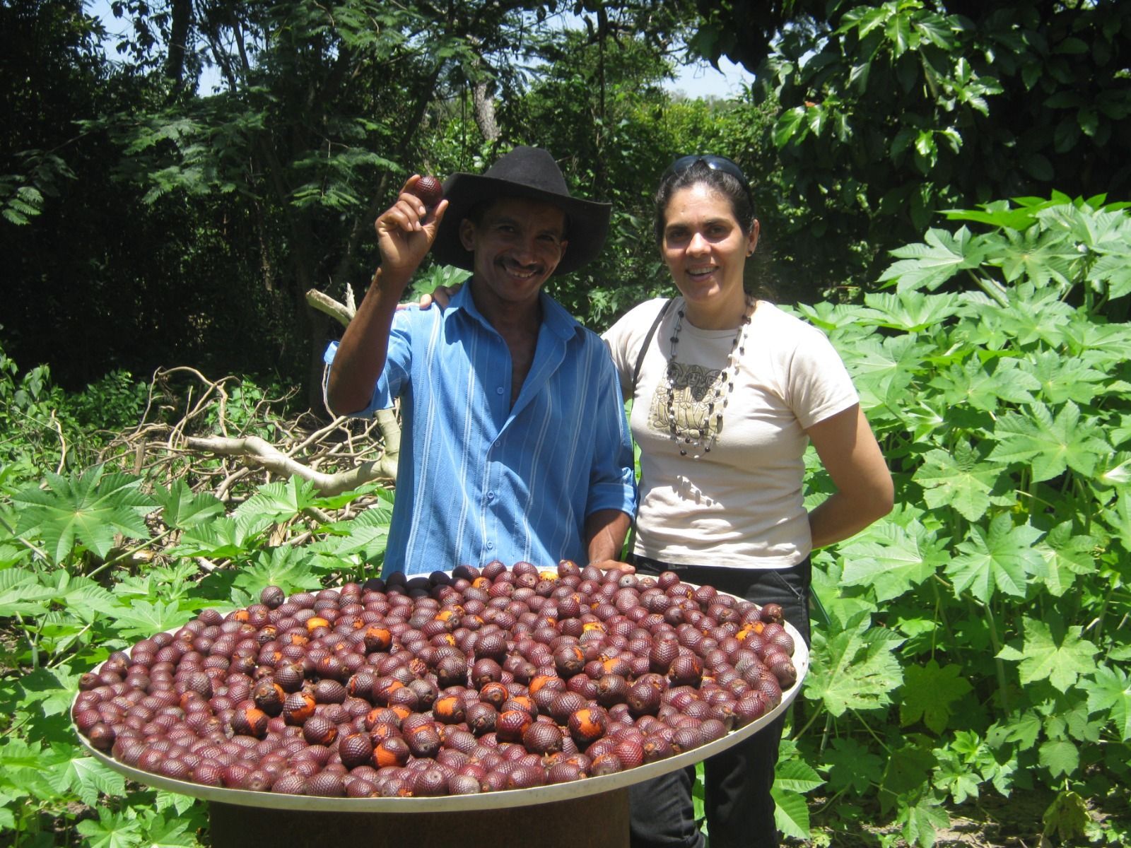 Um homem e uma mulher em pé ao lado de uma bandeja de frutas