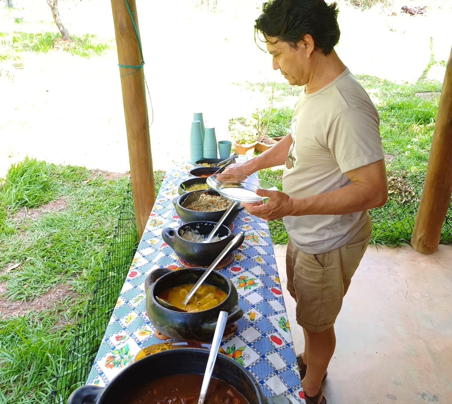 Um homem está parado em frente a uma mesa cheia de potes de comida