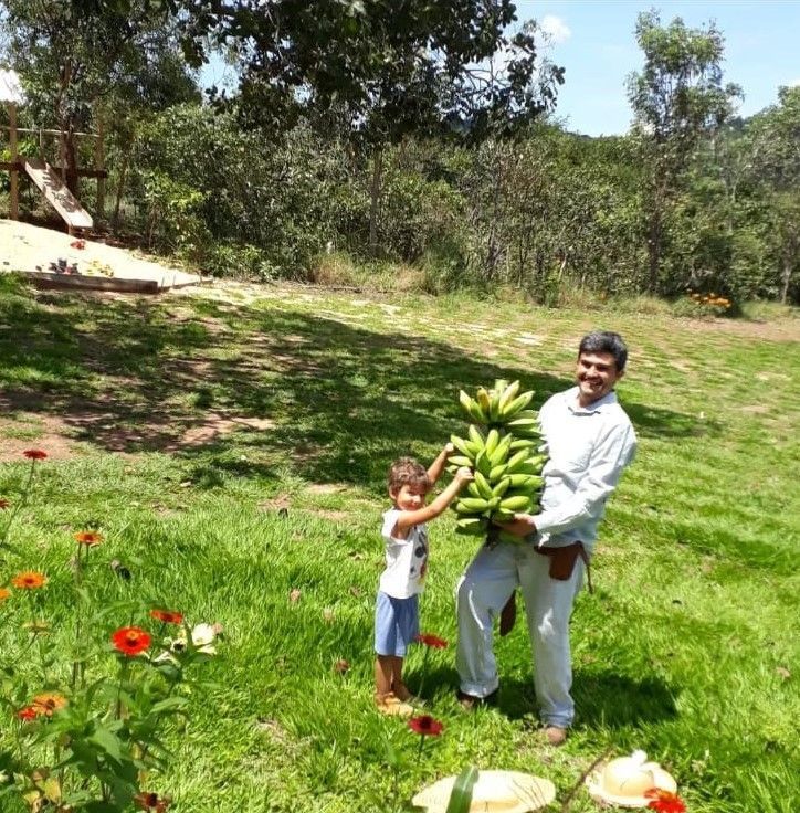 Um homem segurando um cacho de bananas ao lado de uma garotinha