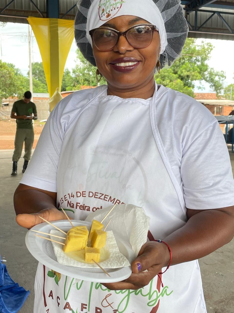 Uma mulher de avental branco segura um prato de comida