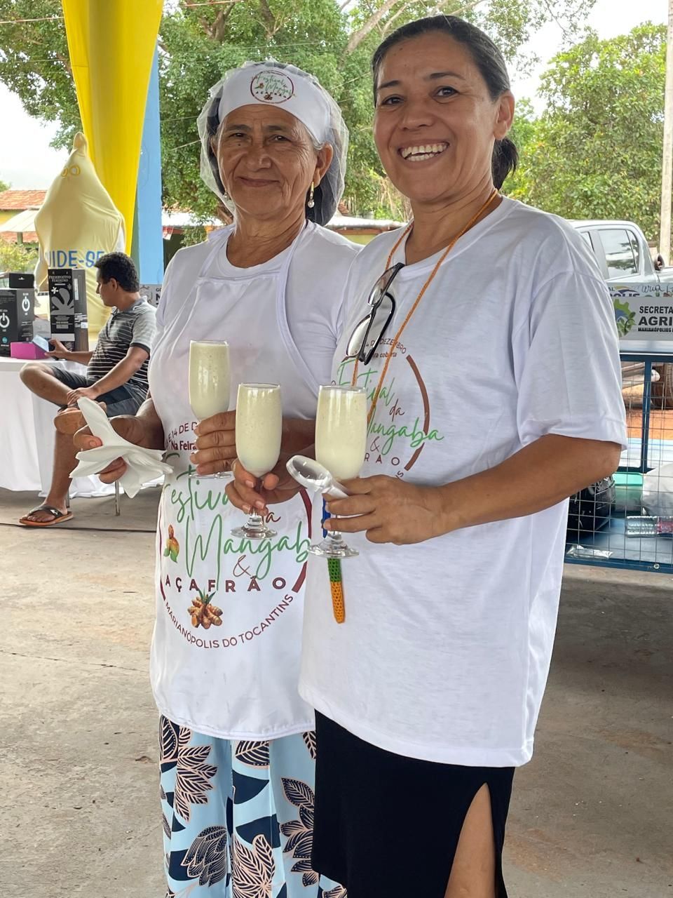 Duas mulheres em pé uma ao lado da outra segurando copos de leite