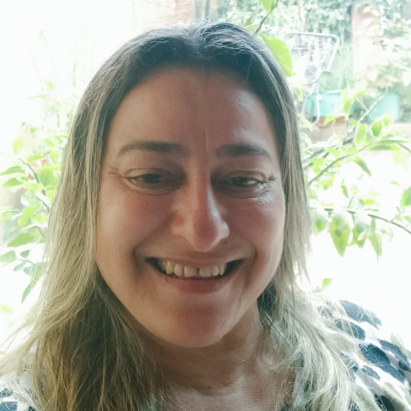 Um close do rosto de uma mulher sorrindo em frente a uma janela.