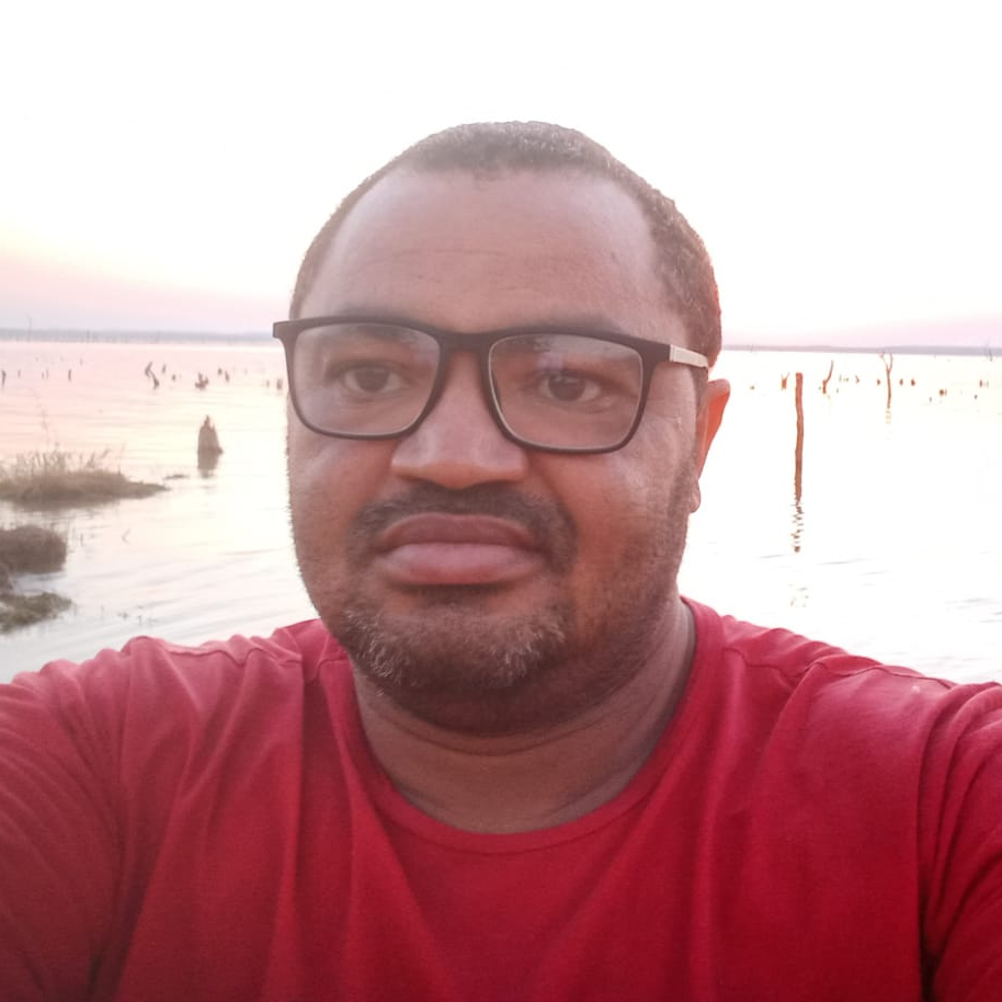 Um homem usando óculos e uma camisa vermelha está tirando uma selfie.