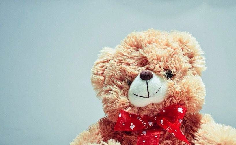 A close up of a teddy bear wearing a red bow tie.