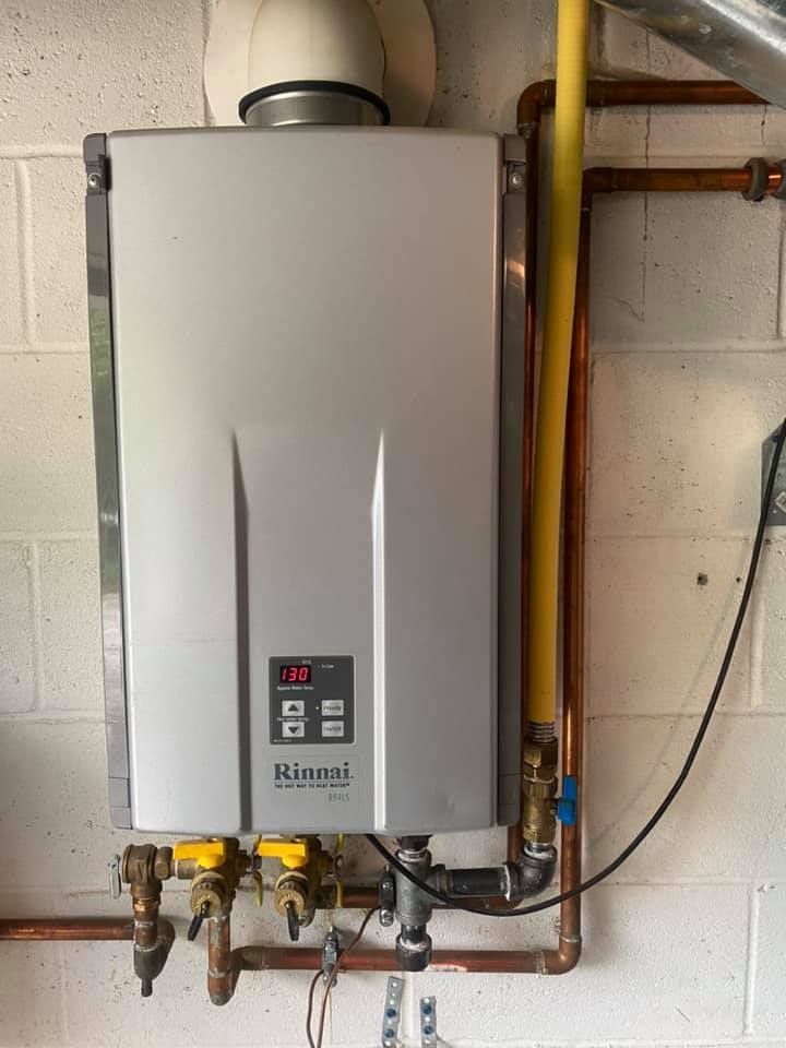 A rinnai water heater is hanging on a wall next to copper pipes.