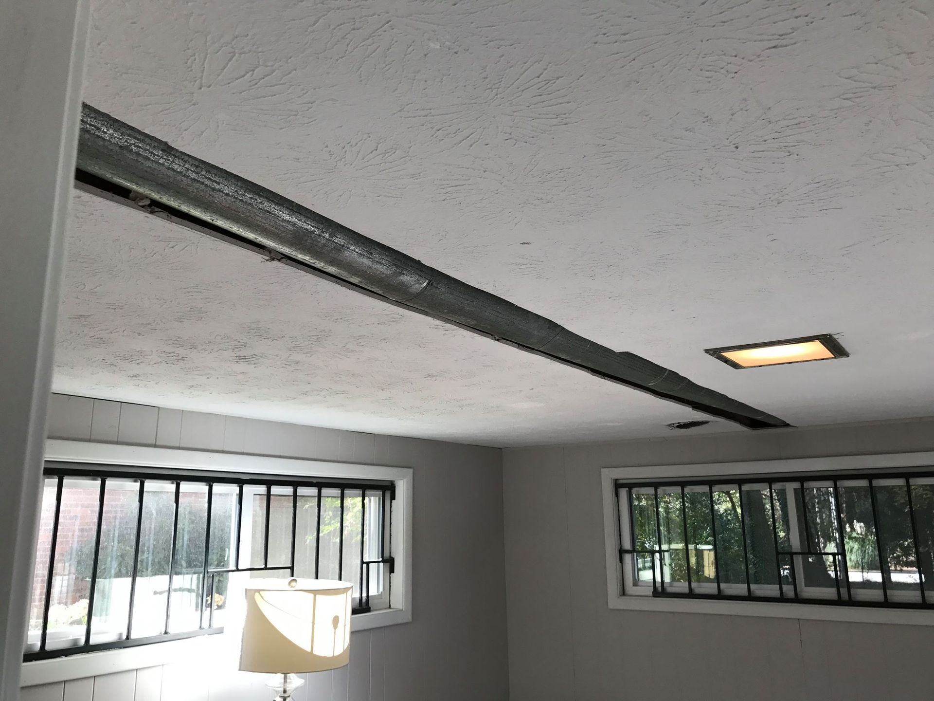 A room with a broken ceiling and a lamp.