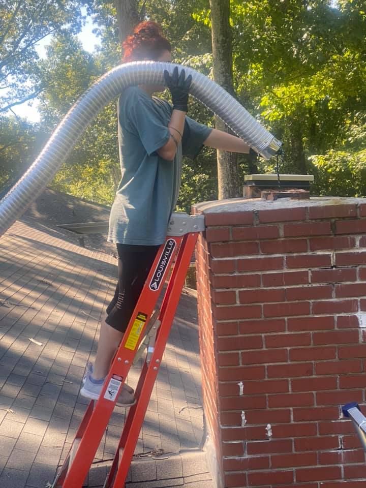 A woman is standing on a ladder next to a brick chimney.