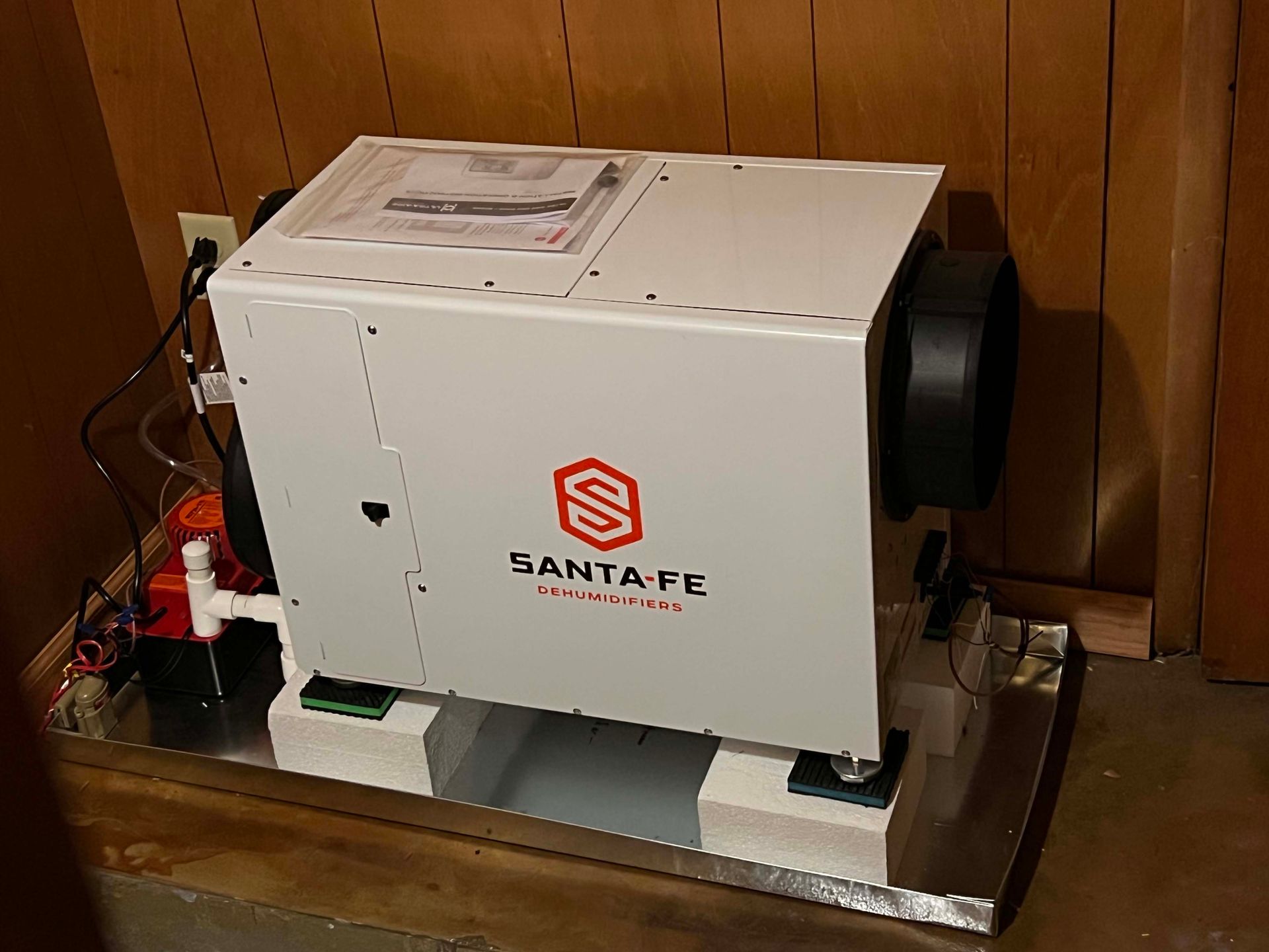 A white santa fe generator is sitting on a wooden floor in a room.