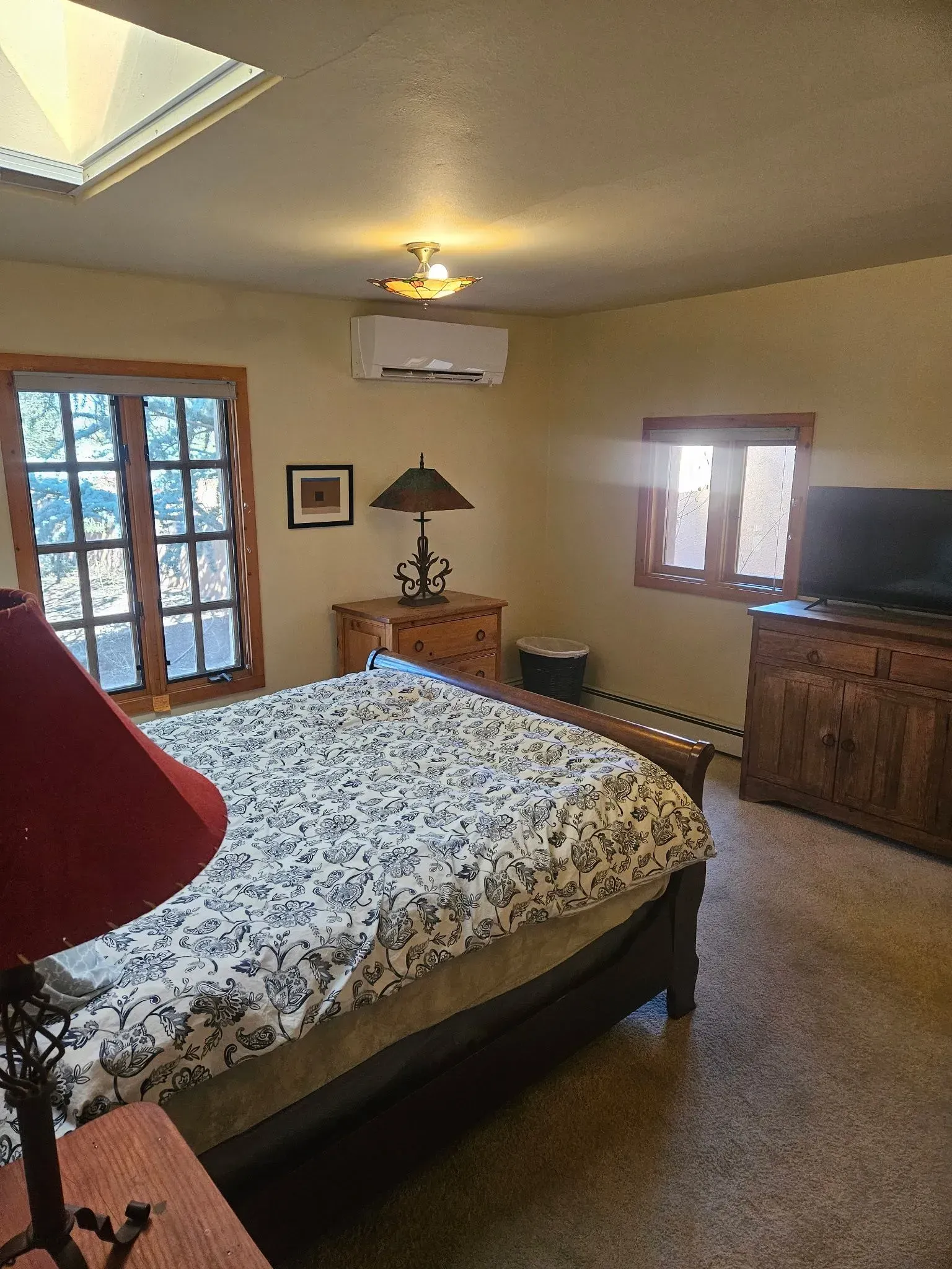 Bedroom with bed, dresser, lamps, window, TV, and air conditioner.