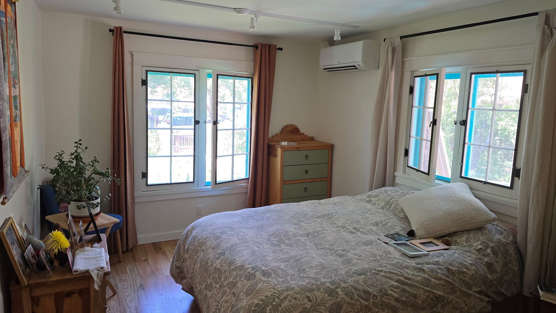 Bedroom with bed, windows, chest of drawers, curtains, and an air conditioning unit.