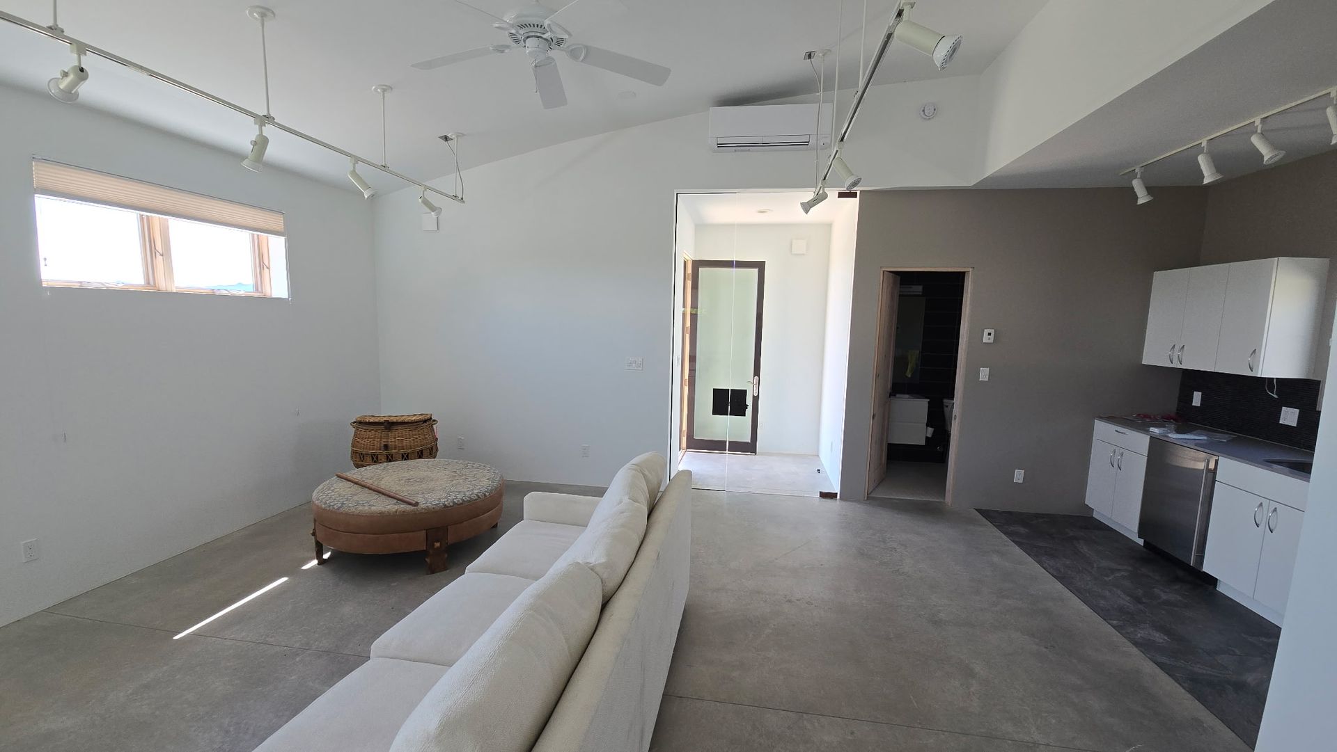 Bedroom with bed, rug, and windows. Pink walls, wooden floor, and a colorful abstract artwork.