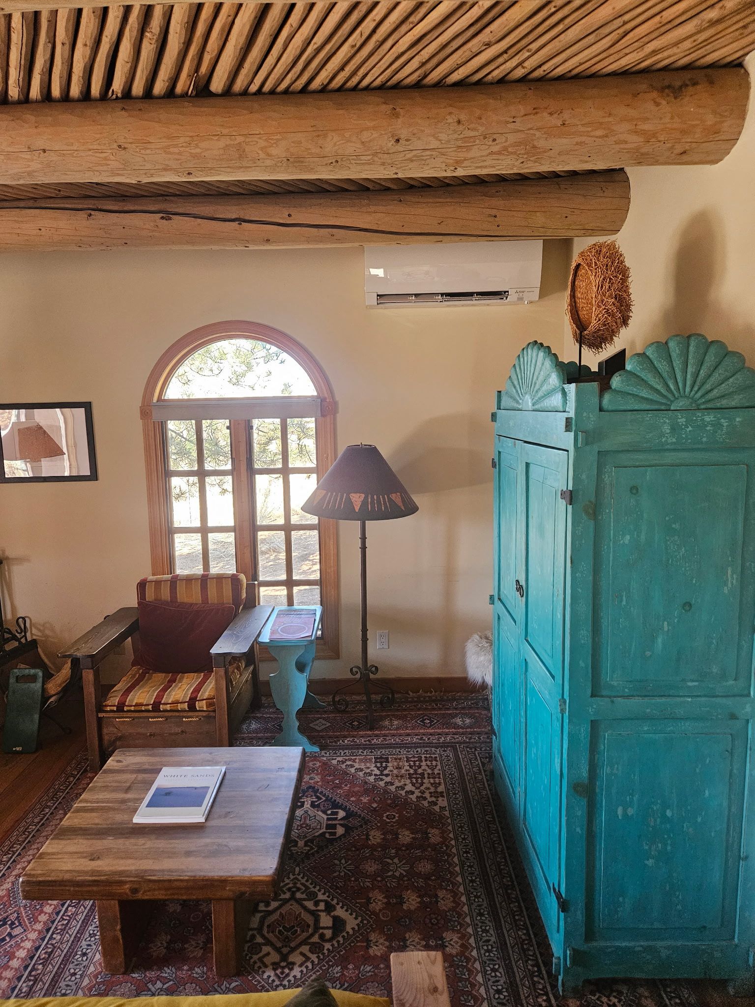 White air conditioner mounted on a yellow wall, wooden ceiling above, doorway below.
