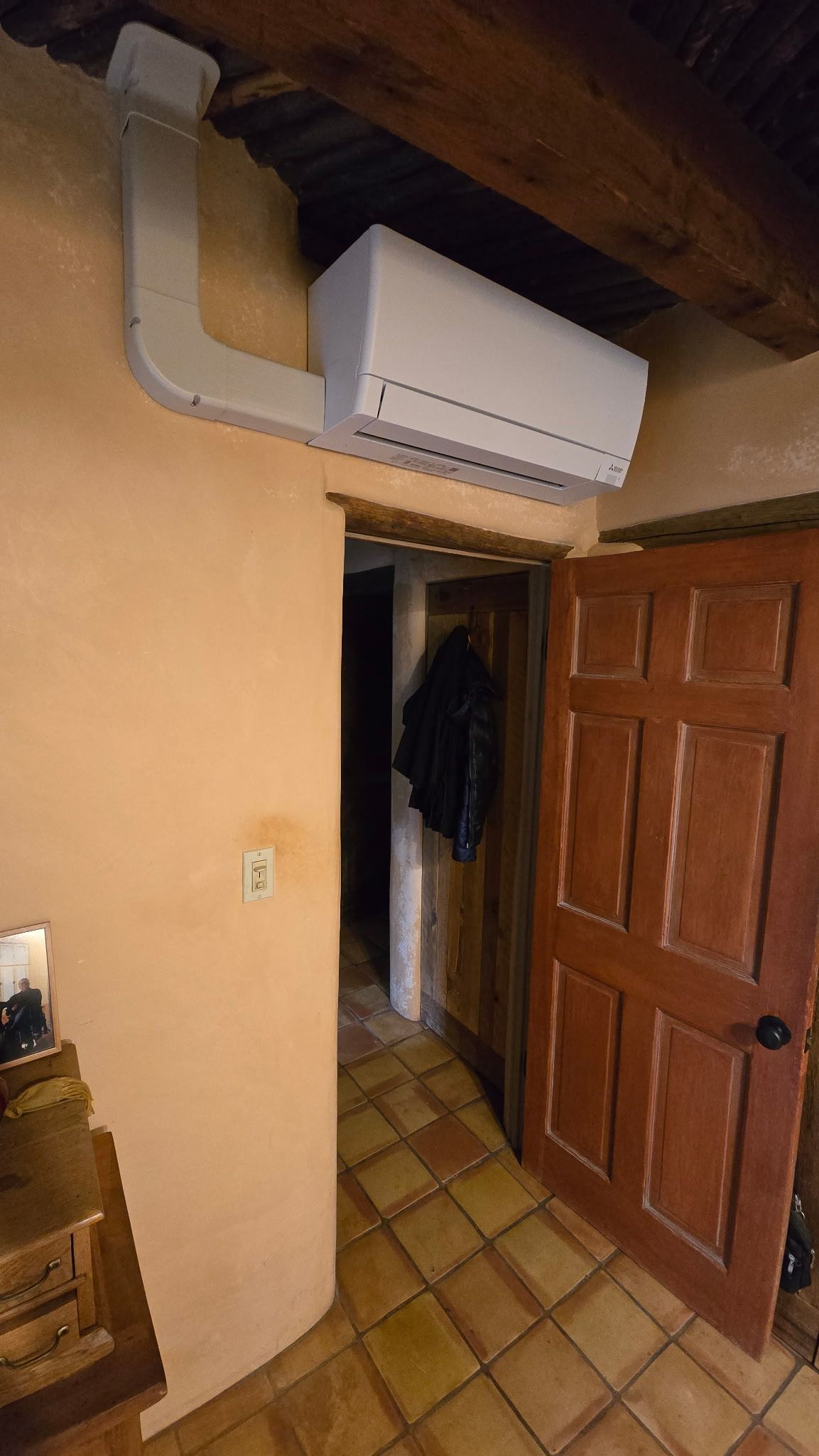 Air conditioning unit on wall above doorway in room with rustic decor.