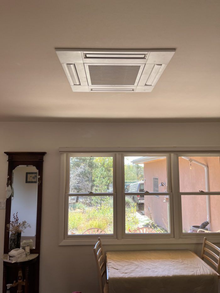 Ceiling light fixture above a table in a dining room; windows show a yard.