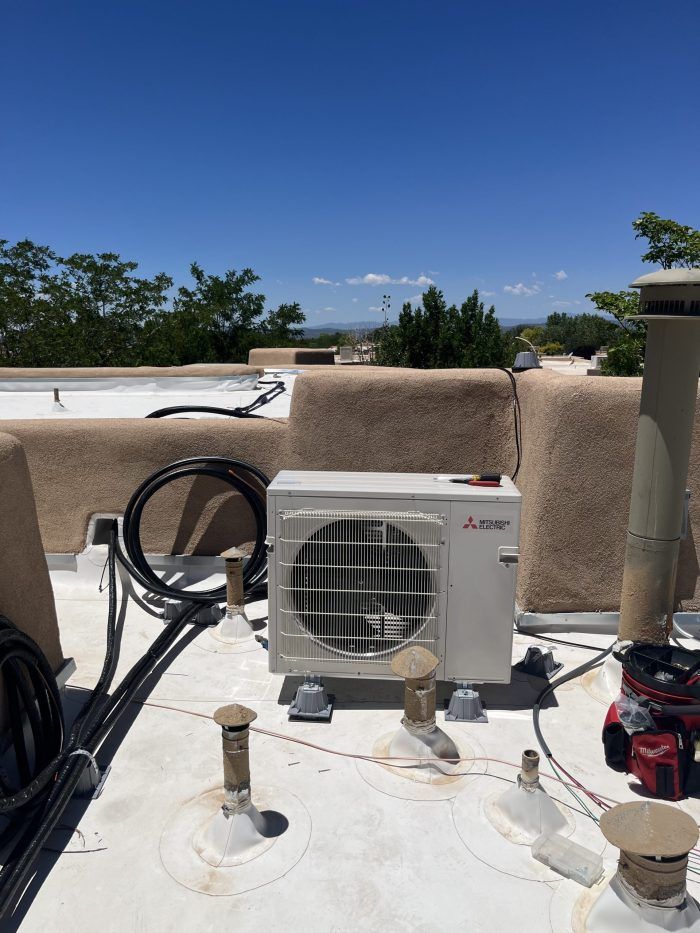 Mitsubishi AC unit on a flat roof under a blue sky, with surrounding equipment.