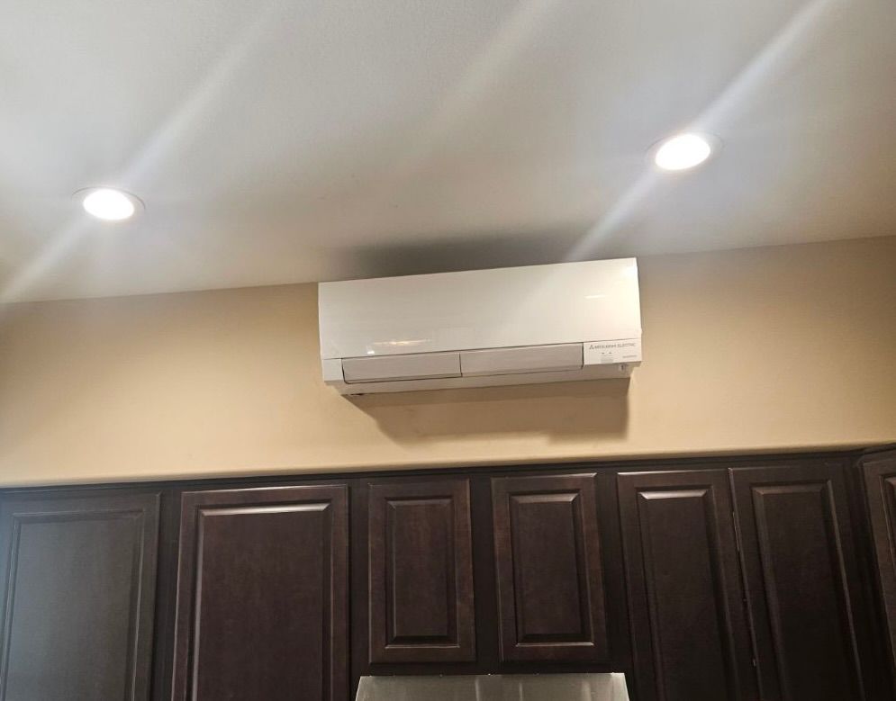 White air conditioner mounted above dark brown kitchen cabinets.