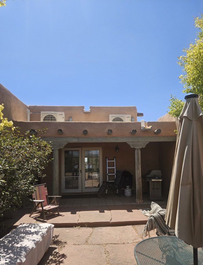 Courtyard with stucco building, french doors, a patio, and an open umbrella.