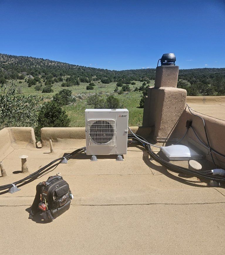 Air conditioning unit on a flat roof with a mountainous landscape backdrop; a toolbox rests nearby.