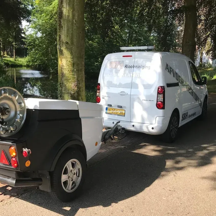 Werkauto van SBH Rioolreiniging met hogedrukreiniger achter de auto, klaar om een wc-verstopping te