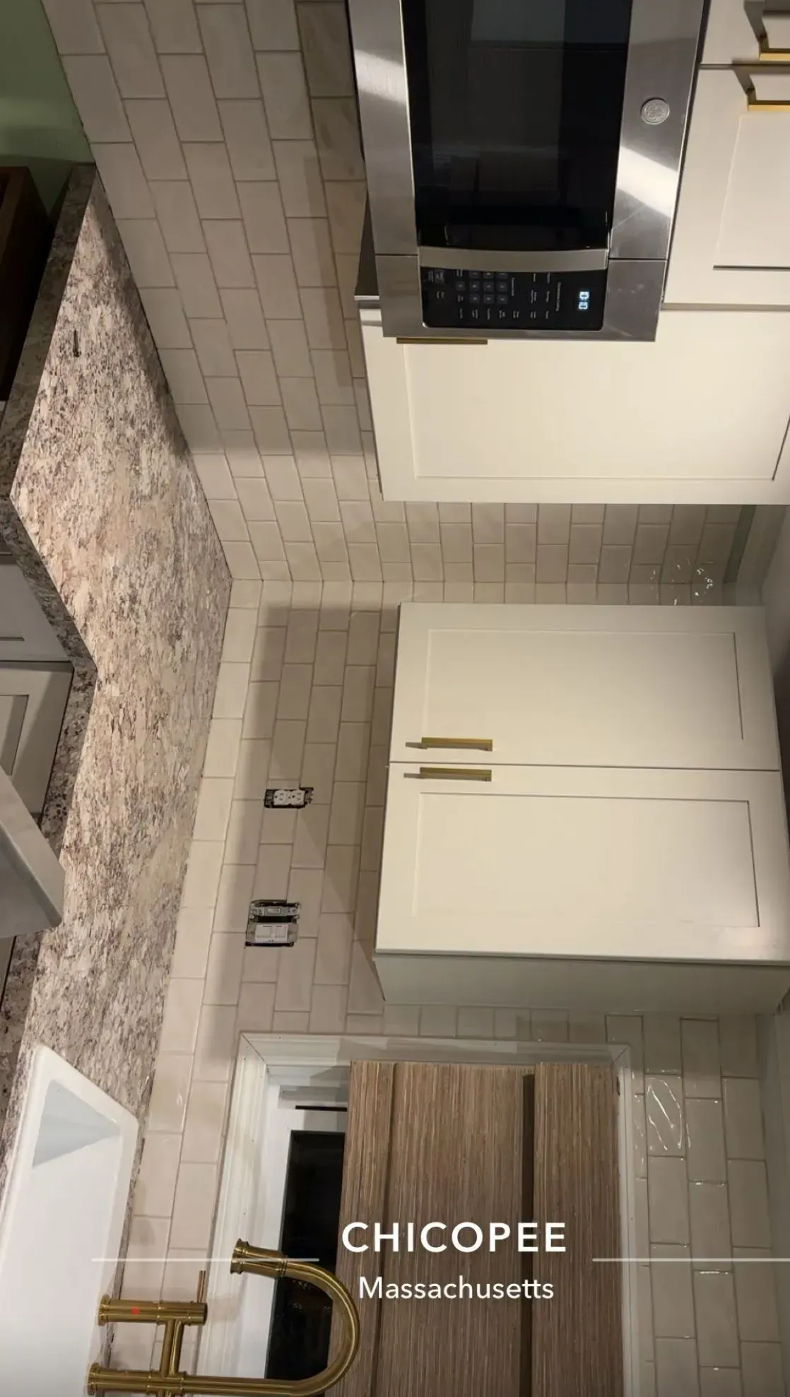 Kitchen with white cabinets, beige backsplash, stainless steel microwave, and Chicopee, Massachusetts text.