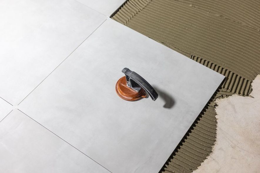 Tile being laid on mortar with a leveling tool.