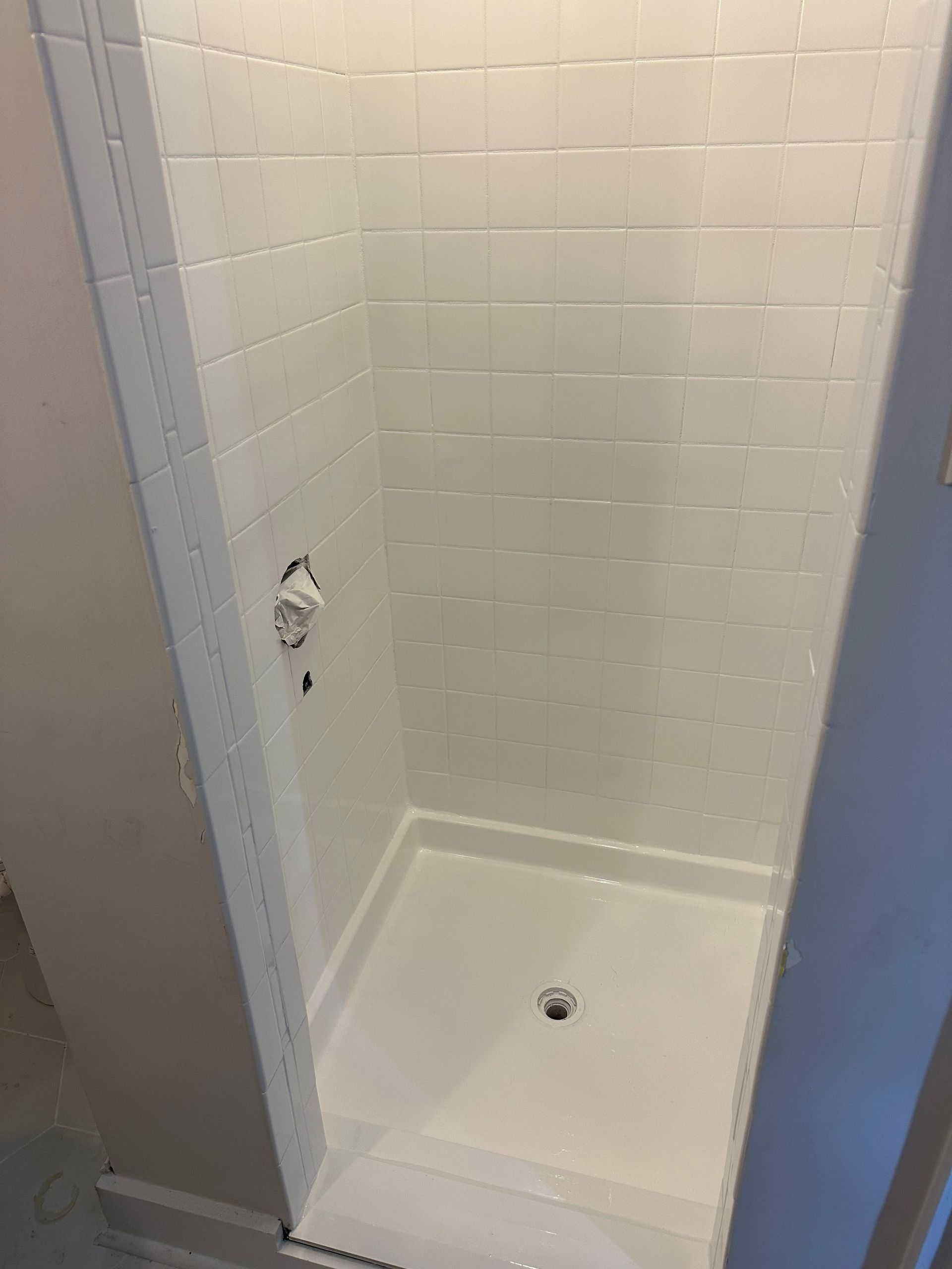White tiled shower with a low threshold and chrome fixtures.