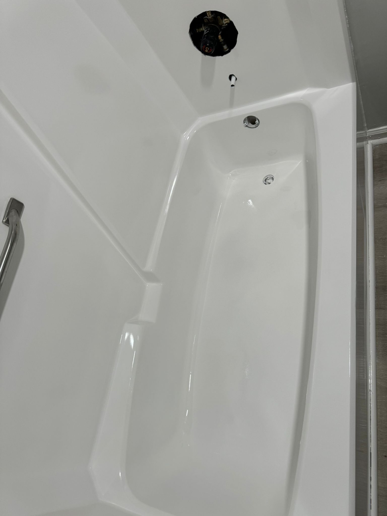 White bathtub and shower enclosure, with showerhead and drain.
