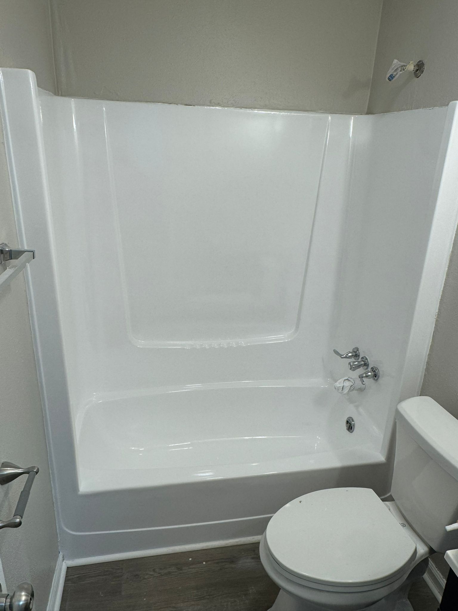 White bathroom with a tub, toilet, and showerhead.