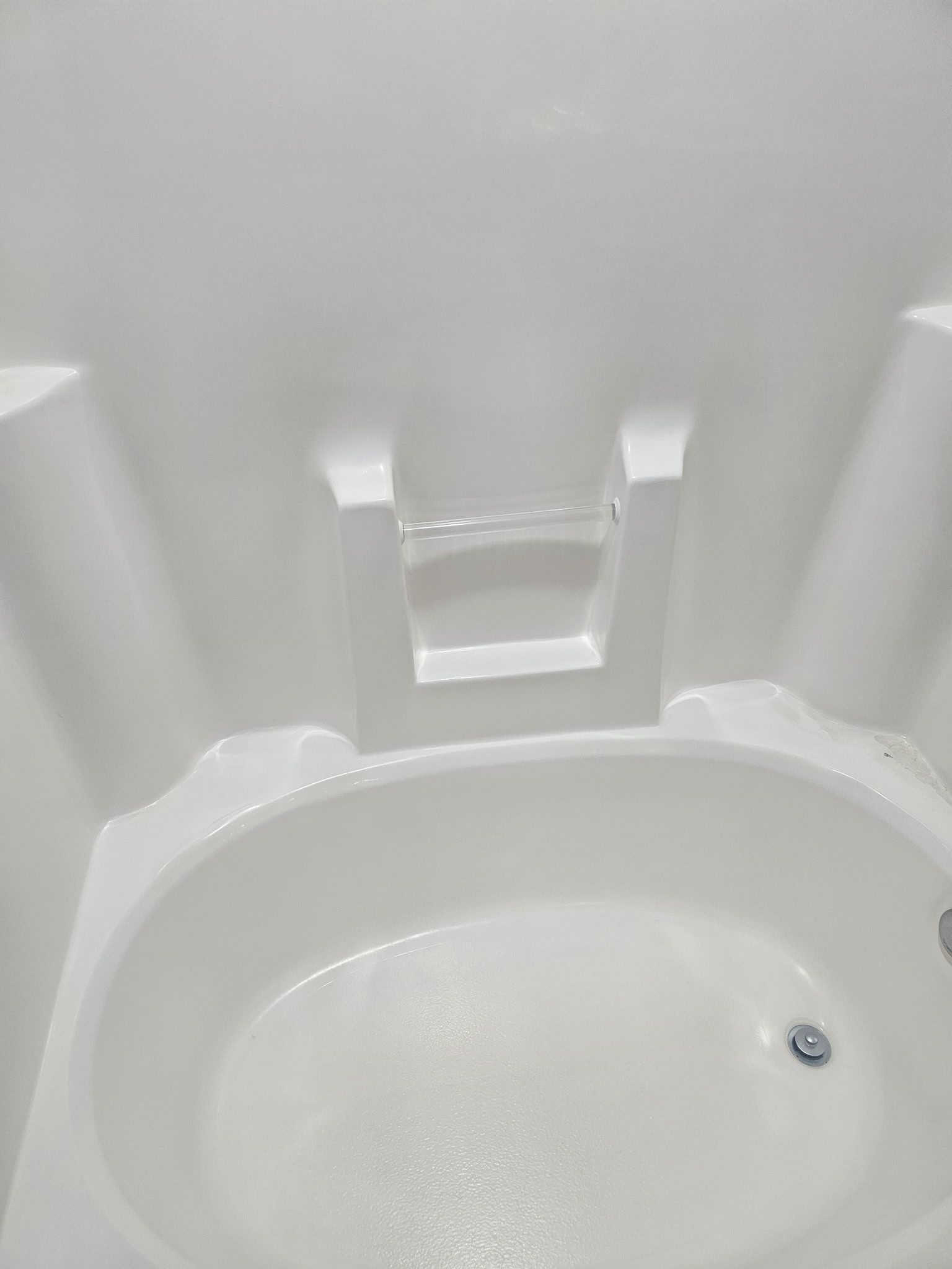 White oval bathtub with a built-in faucet and support structure.