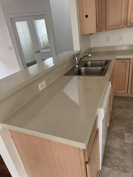 Kitchen with light-colored countertops and cabinets, a double sink, and a door leading outside.
