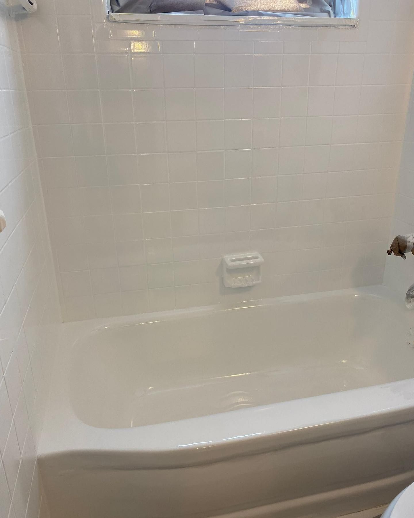 White tiled bathroom with bathtub and soap dish.
