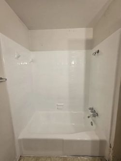 White bathtub and shower surround.