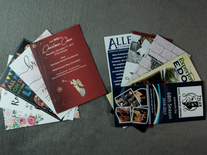 Two stacks of printed cards and brochures on a gray surface. One stack is red and floral, the other has blue and other colors.