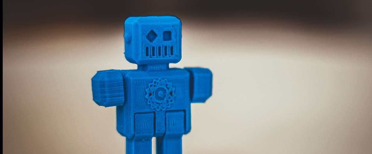 Blue robot toy standing against a blurred neutral background.
