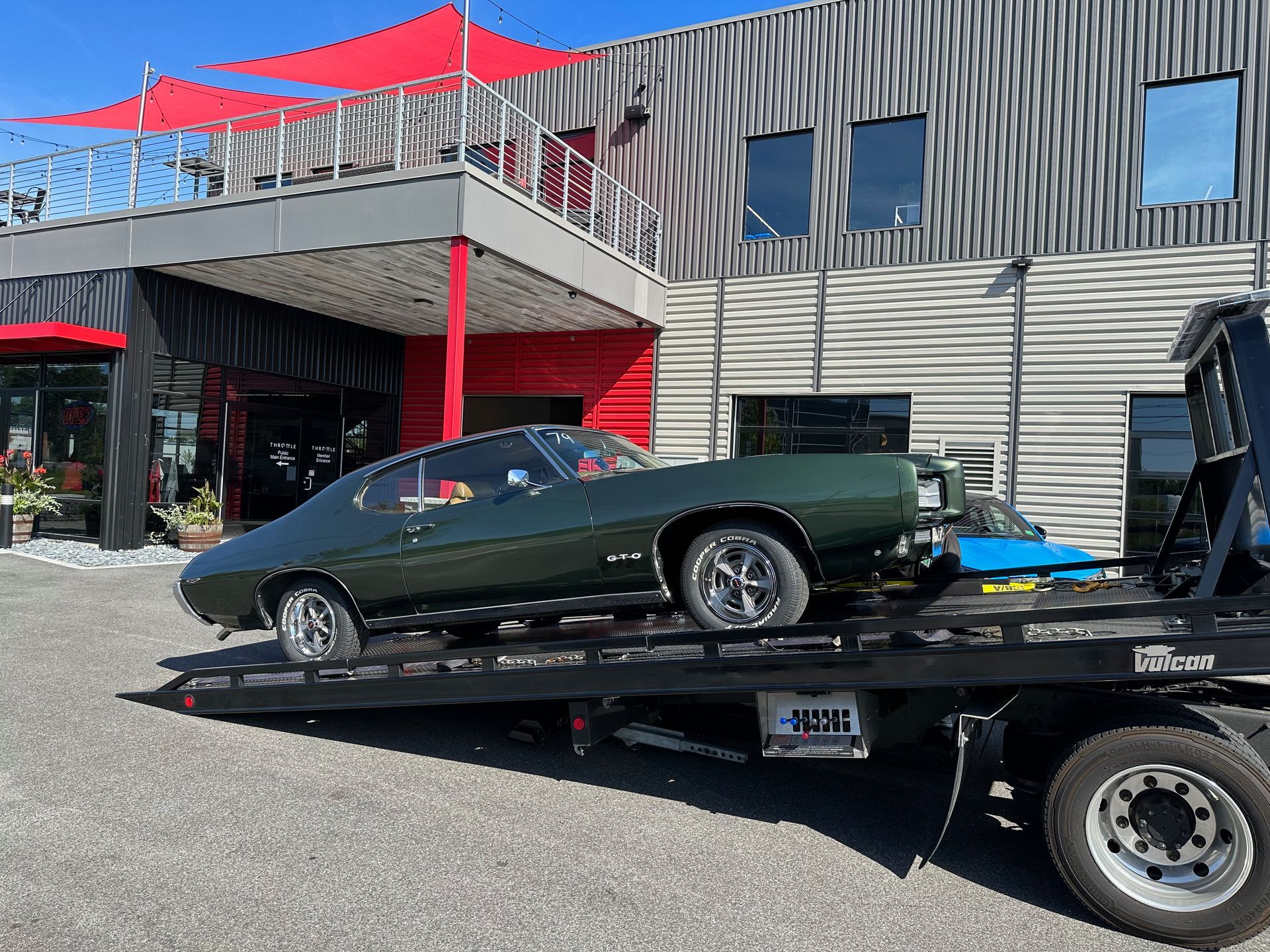 A green car is being towed by a tow truck.