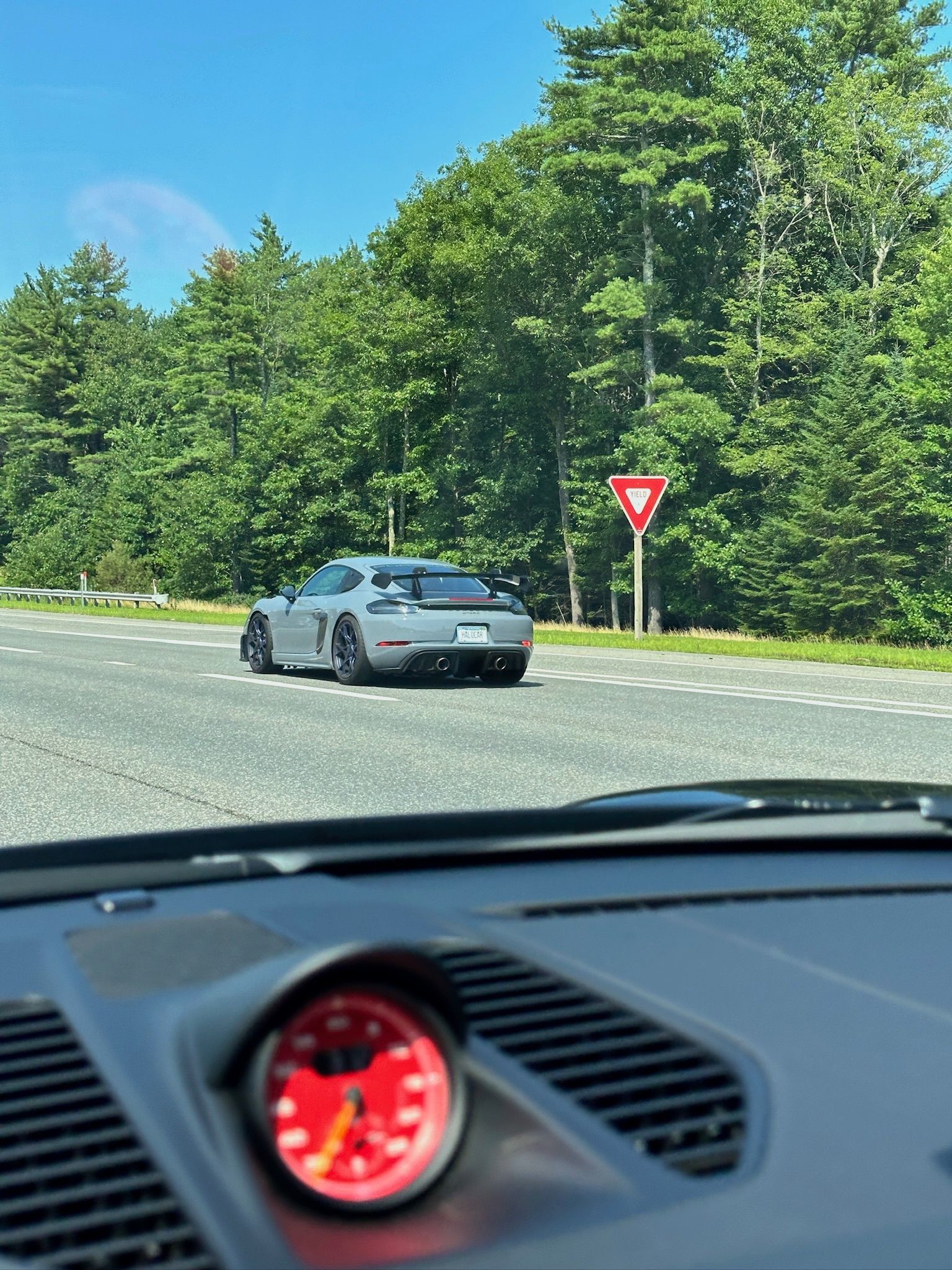 A car is driving down a road with trees in the background.