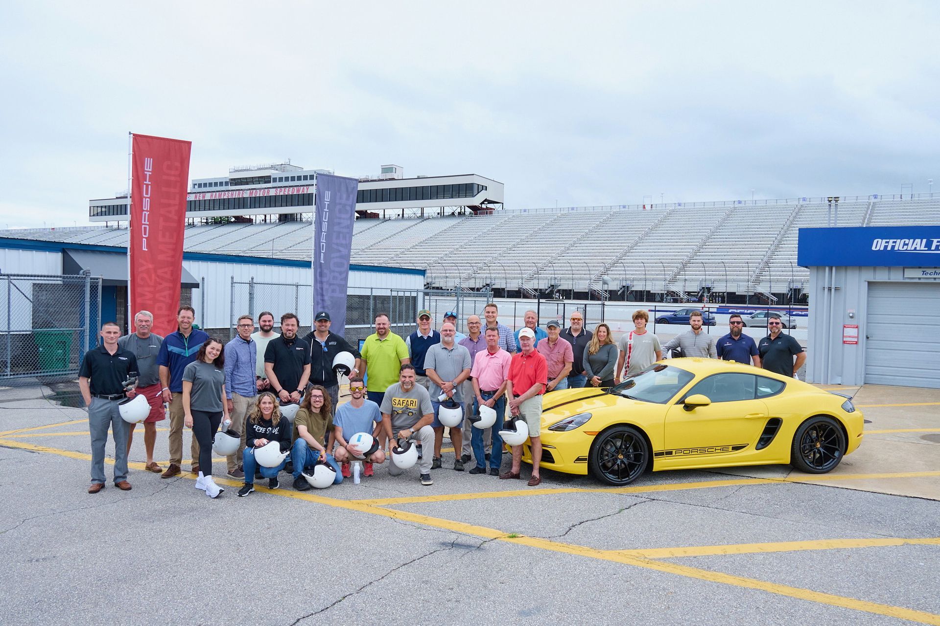 A group of people are posing for a picture in front of a yellow sports car.