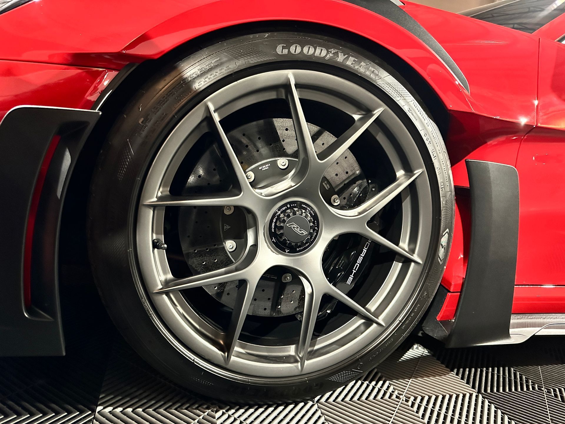 A close up of a red sports car 's wheel and tire.