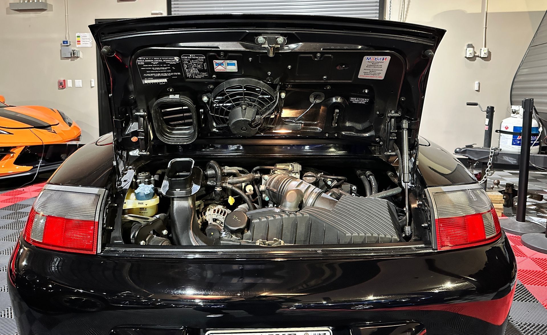 A black car with the hood up in a garage