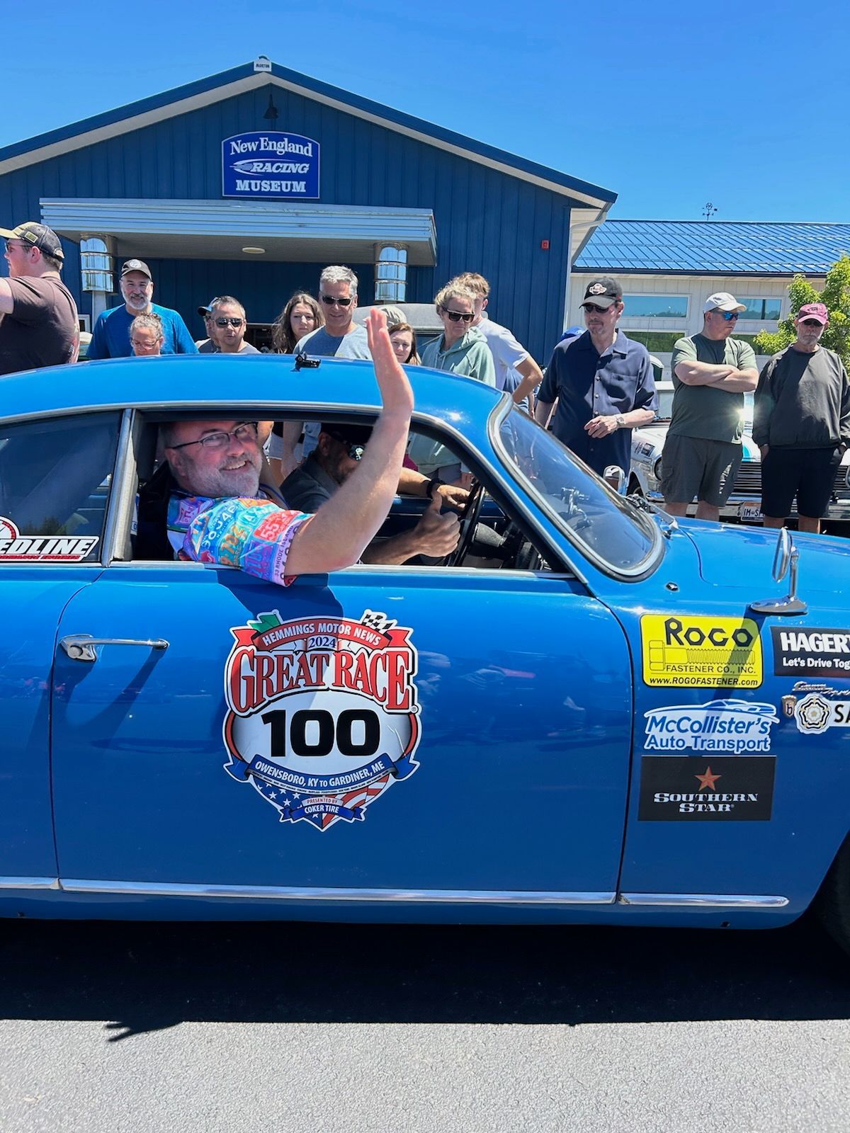 A man is sitting in the driver 's seat of a blue car.