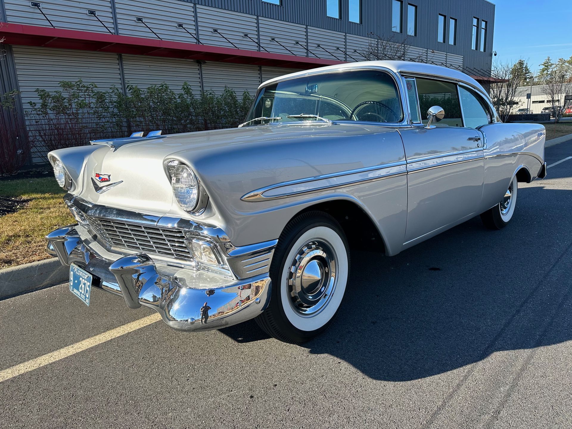 A silver car is parked on the side of the road in front of a building.