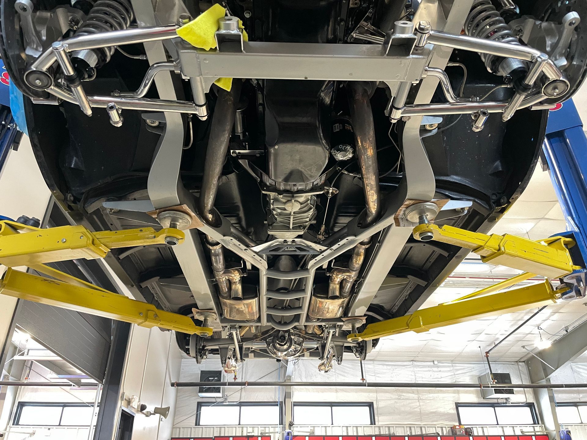 The underside of a car on a lift in a garage.
