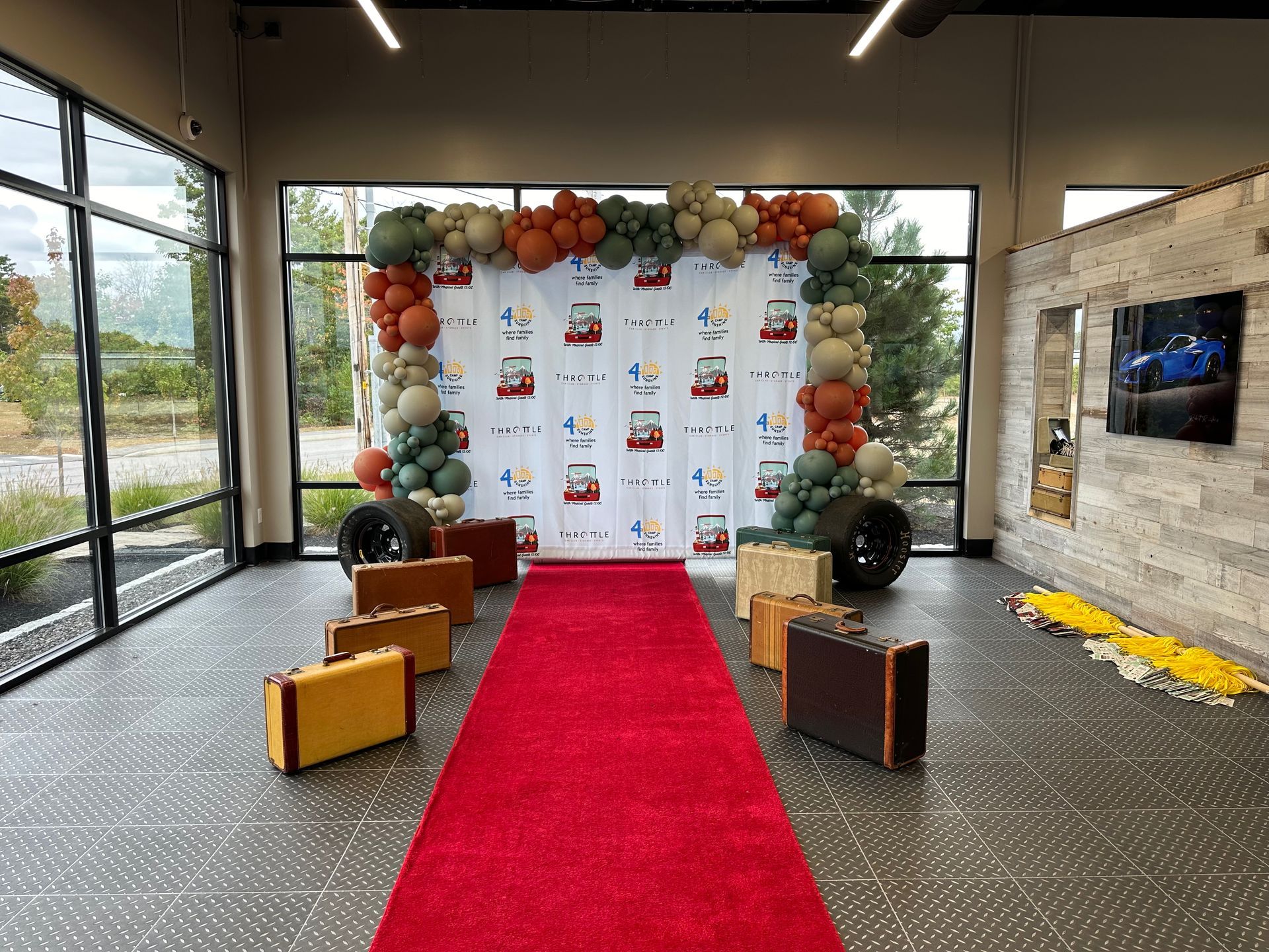 A red carpet is surrounded by suitcases and balloons in a room.