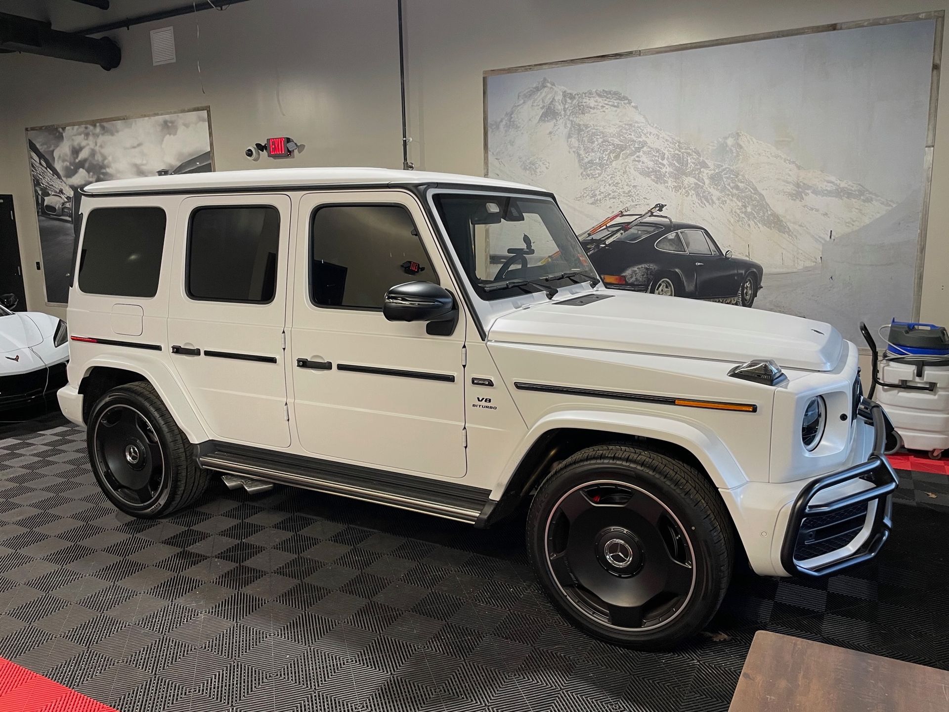 A white mercedes benz g63 amg is parked in a showroom.