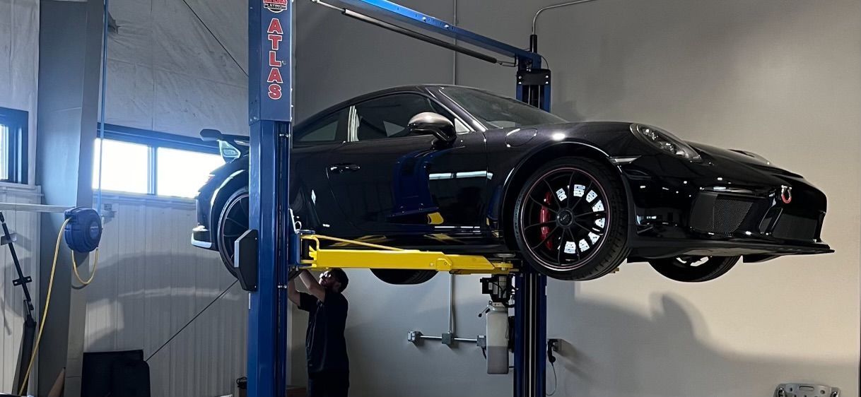 A black sports car is on a lift in a garage.