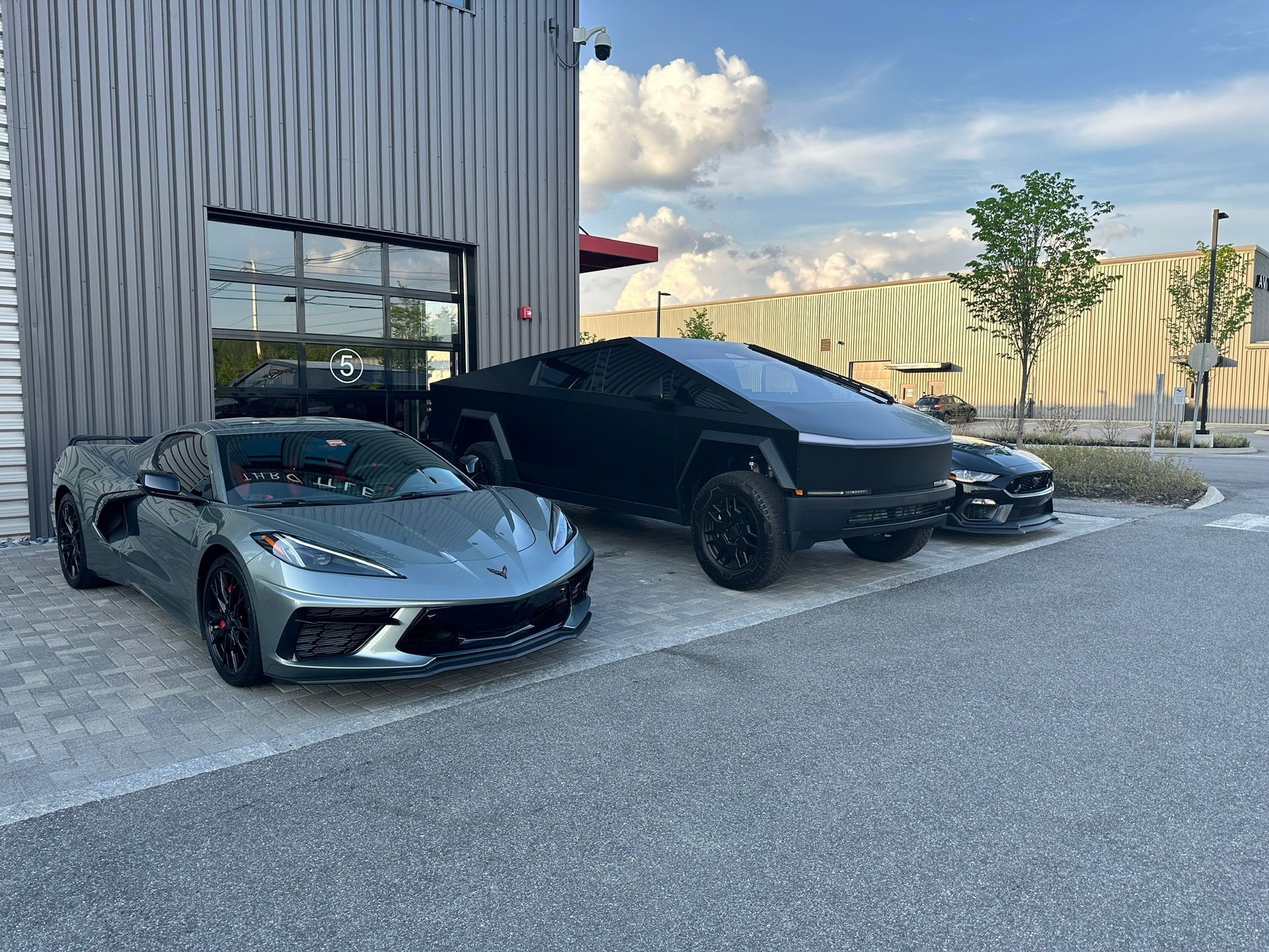 A corvette and a tesla cybertruck are parked next to each other in a parking lot.